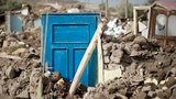 Ein Haus wurde von einem Erdbeben zerstört. Nur noch eine blaue Tür ist in den Trümmern zu sehen.