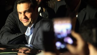 Tsipras wird mit Handys fotografiert und steigt in ein Auto, ein Lächeln auf dem Gesicht.