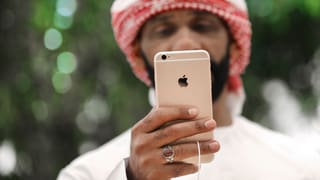 Symbolbild: Ein Mann mit Turban schaut auf sein Smartphone.