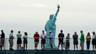 Touristen bewundern von Weitem die Freiheitsstatue in New York.