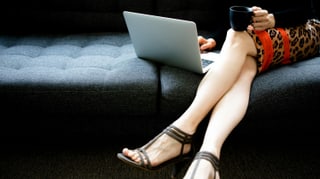 Eine Frau sitzt schick gekleidet vor dem Computer.