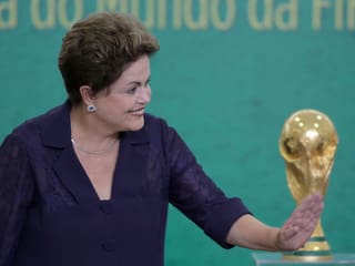 Dilma Rousseff lachend, im Hinergrund der WM-Pokal.