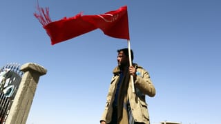 Ein Houthirebell mit einer roten Fahne Ein Houthirebell mit einer roten Fahne