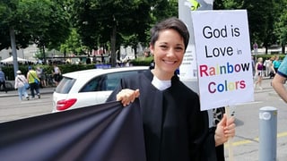 Priscilla Schwendimann mit einem Banner. Darauf steht "God is Love in Rainbow Colors"