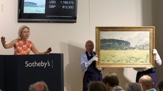 Eine Auktion, bei der zwei Herren ein Gemälde präsentieren.