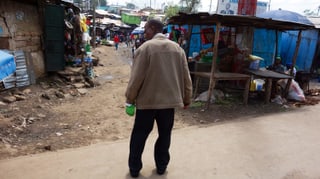 Ein Mann in einem Slum, in der Hand eine Flasche.