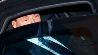 Berlusconis Augen hinter dem Autofenster, das einen Spalt geöffnet ist.