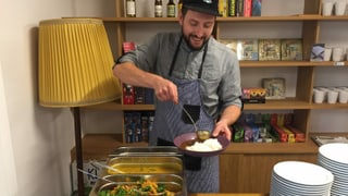 Ein Mann mit Baseballkappe schöpft Essen in eine Schale. Ein Mann mit Baseballkappe schöpft Essen in eine Schale.