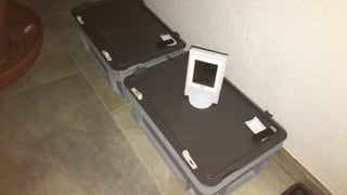 Graue Transportboxen mit Deckel. Auf einer steht ein Termometer Graue Transportboxen mit Deckel. Auf einer steht ein Termometer