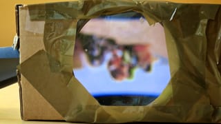 Wir blicken durch die Lupe auf den Bildschirm des Smartphones. Wir blicken durch die Lupe auf den Bildschirm des Smartphones.