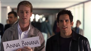 Norton und ein anderer Mann warten am Flughafen auf jemanden, Norton hält ein Schild mit der Aufschrift ("Anna Banana").