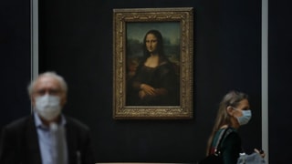 Menschen mit Schutzmasken vor dem Bild der Mona Lisa.
