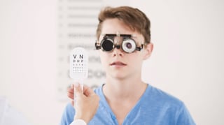 Ein junge steht vor einem Plakat für den Sehtest. Ein junge steht vor einem Plakat für den Sehtest.