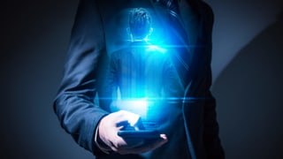 Ein Mann hält ein Smartphone in der Hand, vor ihm erscheint eine Projektion seiner selbst. Ein Mann hält ein Smartphone in der Hand, vor ihm erscheint eine Projektion seiner selbst.