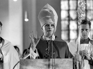Der Papst hält eine Ansprache und hält die rechte Hand in die Luft.