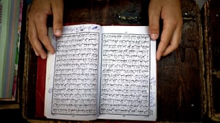Ein pakistanischer Schüler blättert im Koran.