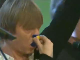 Ein Mann hält sich ein kleines Plastikobjekt an Nase und Mund, wo er reinbläst. 