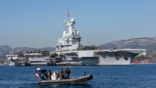 Der französische Flugzeugträger Charles de Gaulle, davor ein Schlauchboot.