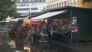 2 Marktstände. Im Vordergrund Kleider, im Hintergrund Blumen 2 Marktstände. Im Vordergrund Kleider, im Hintergrund Blumen
