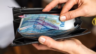 Hand ergreift in Portemonnaie einen 100-Franken-Schein.