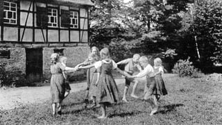 Kinder spielen vor einem Landhaus.