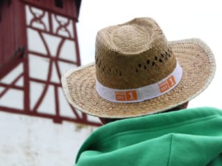 Ein Wanderer mit Strohhut blickt auf die Riegel-Fassade der Probstei Wagenhausen.