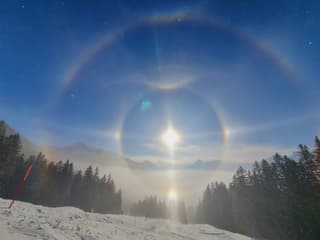 Halo mit 2 Nebensonnen, einem schwachen Horizontalkreis, einer Untersonne, einer unteren Lichtsäule, dem oberen Berührungsbogen, dem konkaven Parrybogen, dem 46°-Halo, im Ansatz dem Zirkumzenitlabogen und 46°-Berührungsbogen.