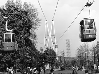 Die Gondeln der Zürichsee-Seilbahn 1959 schweben über die Besucher.