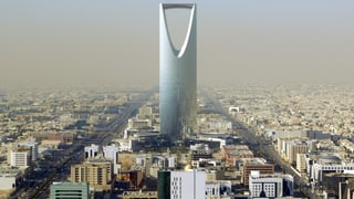 Stadtpanorama mit riesigem verglastem Turm, der im oberen Drittel einen dreieckigen Hohlraum hat.
