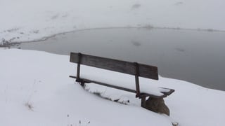 Eine Bank an einem See im Schnee