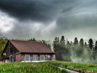 Dunkle Wolken mit vielen Pollen in der Luft. Im Vordergrund ist ein Bauernhaus.