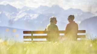 Zwei ältere Frauen sitzen auf einer Bank vor einem Bergpanorama Zwei ältere Frauen sitzen auf einer Bank vor einem Bergpanorama