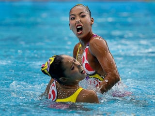 Schwimmerinnen im Wasser, verzerrte Gesichter.