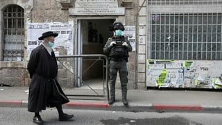Jüdisch gekleidete Person mit Schutzmaske und israelischer Soldat.