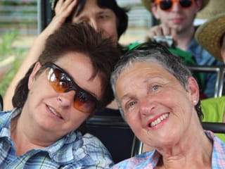 Blanca Imboden und eine Wanderin sitzen im Oldtimer-Postauto und blicken zufrieden in die Kamera.