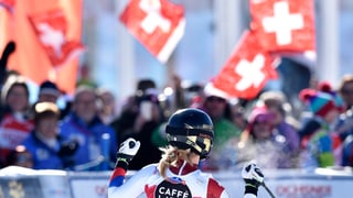 Lara Gut vor Fans, die alle die Schweizer Fahne schwenken.