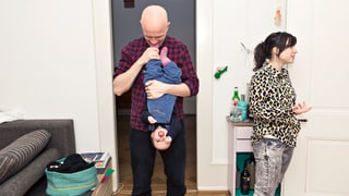 Mann spielt mit Kind und Frau redet mit jemandem Mann spielt mit Kind und Frau redet mit jemandem