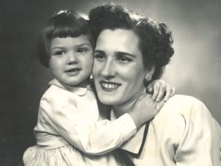 Schwarz-Weiss-Fotografie mit einem kleinen Mädchen, das seine Mutter umarmt.