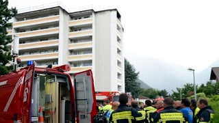 Feuerwehrleute stehen vor dem Hochhaus.