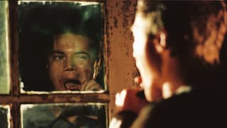 Ein Mann puhlt vor dem Spiegel ein Stück Metall aus seinem Mund.