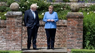 Angela Merkel und Boris Johnson in einem Garten stehend.