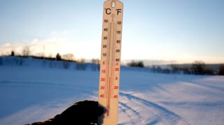 Thermometer vor einer Winterlandschaft.