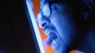 Ein Mann mit Brille schaut mit geöffnetem Mund und grossen Augen in einen Monitor.