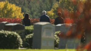 Joe Biden und zwei jüngere Familienmitglieder auf einem Friedhof.