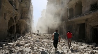 Häuserschlucht in Aleppo mit der Trümmerübersähten Strasse dazwischen und zwei Menschen darin