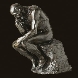 eine Statue, die einen Mensch denkend auf einem Stein sitzend zeigt eine Statue, die einen Mensch denkend auf einem Stein sitzend zeigt