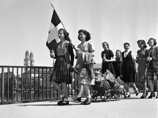 Mädchen ziehen am 8. Mai 1945, dem Tag der Kapitulation Deutschlands, mit einer Schweizer Fahne und einem geschmückten Leiterwagen über die Quaibrücke in Zürich. 