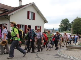 Die «Querfeldeins»-Equipe wandert fröhlich an einem Haus vorbei.