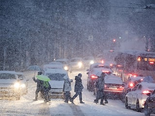Personen und Autos auf schneebedeckter Strasse.