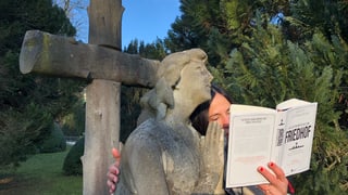 Annette König umarmt eine Friedhofsfigur und hält das Buch «Die letzten Meter bis zum Friedhof» in der Hand.